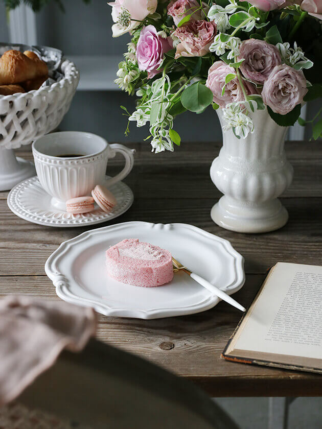 ピンクをテーマしたテーブルコーディネートの花にマカロンやロールケーキを合わせてティータイム